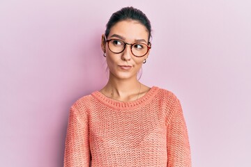 Young caucasian woman wearing casual clothes and glasses smiling looking to the side and staring...