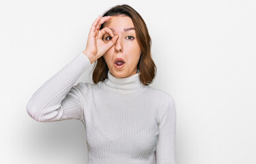 Young caucasian girl wearing casual clothes doing ok gesture shocked with surprised face, eye looking through fingers. unbelieving expression.