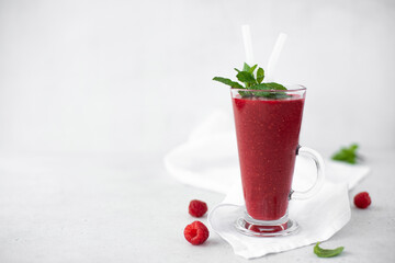 berry smoothie with fresh raspberries and mint in a tall glass glass