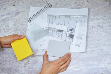 soft focus On the table is a mock-up of a kitchen, an example of a palette of facades and drawer bodies and a handle for the door. girl orders furniture for the kitchen in the salon. close-up