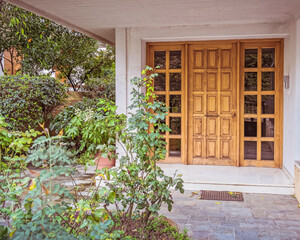 contemporary apartment building entrance with natural wood and glass door through a small garden