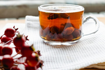 Fruit tea made from berries and rosehip fruits in a transparent glass mug. Hot drink like fresh compote on a white towel