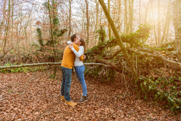 Beautiful young couple hugging in autumnal forest at sunset.Romantic , love and friendship lifestyle.Travel concept.