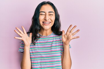 Hispanic teenager girl with dental braces wearing casual clothes celebrating crazy and amazed for success with arms raised and open eyes screaming excited. winner concept - obrazy, fototapety, plakaty