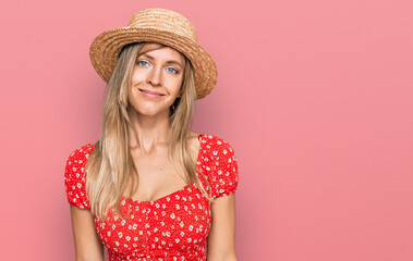 Beautiful caucasian woman wearing summer hat relaxed with serious expression on face. simple and natural looking at the camera.