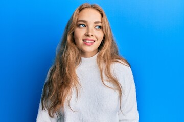 Fototapeta premium Beautiful blonde caucasian woman wearing casual winter sweater looking to side, relax profile pose with natural face and confident smile.