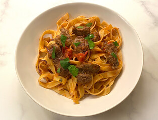 Classic dish. Grilled beef fillet strips with tagliatelle pasta in tomato sauce.