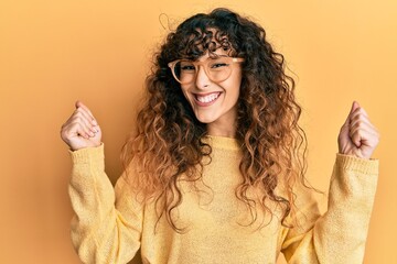 Young hispanic girl wearing casual clothes and glasses screaming proud, celebrating victory and...