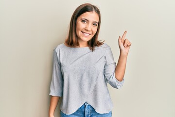Young beautiful woman wearing casual clothes smiling with an idea or question pointing finger up with happy face, number one