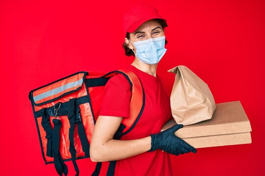 Young Hispanic Woman Wearing Medical Mask Holding Take Away Food Smiling And Laughing Hard Out Loud Because Funny Crazy Joke.