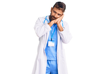 Young hispanic man wearing doctor uniform and stethoscope sleeping tired dreaming and posing with hands together while smiling with closed eyes.