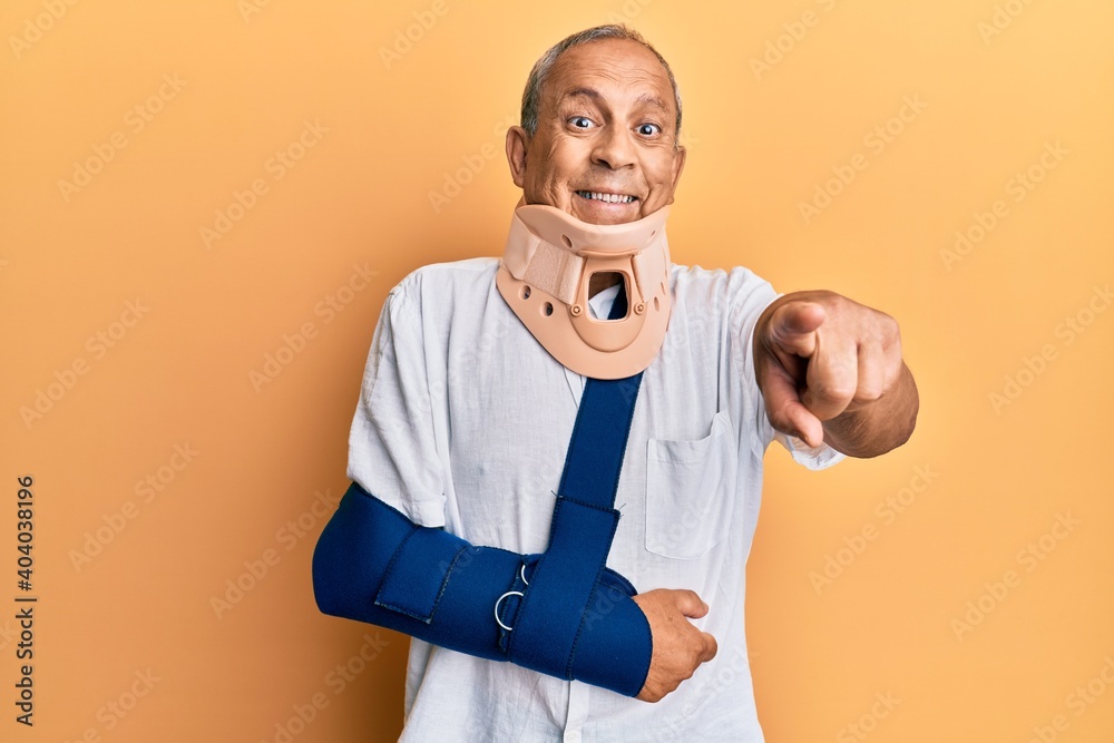 Poster handsome mature senior man wearing cervical collar and arm on sling pointing to you and the camera w