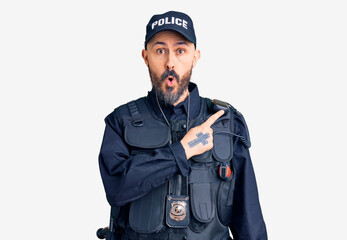 Young handsome man wearing police uniform surprised pointing with finger to the side, open mouth amazed expression.