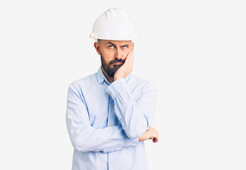 Young handsome man wearing architect hardhat thinking looking tired and bored with depression problems with crossed arms.