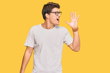 Handsome caucasian man wearing casual clothes and glasses shouting and screaming loud to side with hand on mouth. communication concept.