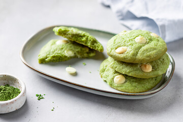 stack of green tea matcha cookies with white chocolate in plate on gray background. Health care, diet and nutrition concept. close-up