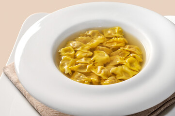 ravioli del plin in broth, typical Piedmontese stuffed pasta from the Langhe, Italy, in white plate