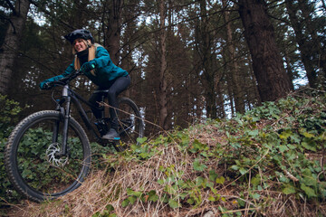 Cyclist girl with mountain bike descending down mtb trail in forest