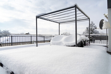 Wintereinbruch: Schnee bedeckt das Mobiliar einer luxuriösen Sonnenterrasse, über der sich ein leerer Pavillon erhebt