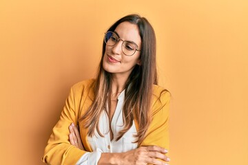 Young beautiful woman wearing business style and glasses looking to the side with arms crossed convinced and confident