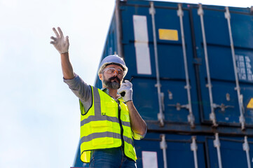 Fototapeta na wymiar Logistics engineer stand on and Pointing up around Shipping container stacker in commercial transport port