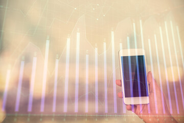 Double exposure of forex chart sketch hologram and woman holding and using a mobile device. Stock market concept.