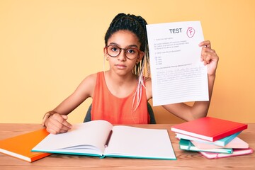 Young african american girl child with braids showing failed exam thinking attitude and sober...