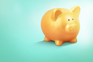 Close up of gold piggy bank on pastel green background