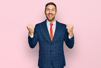 Handsome man with beard wearing business suit and tie celebrating surprised and amazed for success with arms raised and open eyes. winner concept.