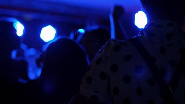 A young guy in a shirt with polka dots and suspenders, dancing on a dance stage among other people. Stylish guy on the dance floor.