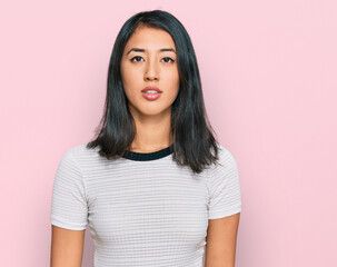 Fototapeta premium Beautiful asian young woman wearing casual white t shirt relaxed with serious expression on face. simple and natural looking at the camera.