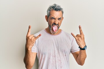 Middle age grey-haired man wearing casual clothes shouting with crazy expression doing rock symbol with hands up. music star. heavy concept. - Powered by Adobe