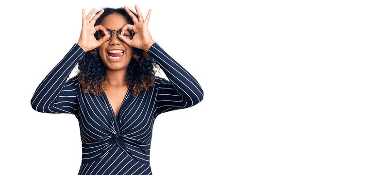 Young african american woman wearing casual clothes and glasses doing ok gesture like binoculars sticking tongue out, eyes looking through fingers. crazy expression.