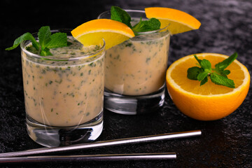 
Orange and mint smoothie on a black background.
Close-up.