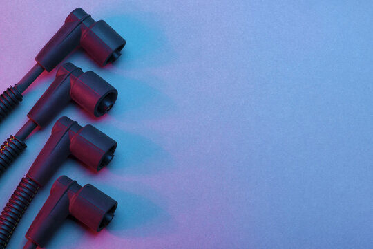 Black ignition wires of a high voltage for spark plug on blue and red background. Car parts. Top view.
