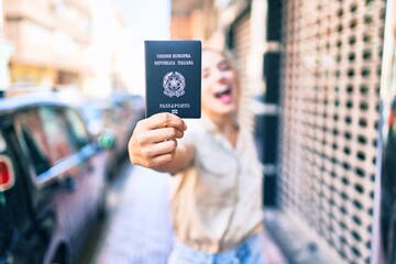Young beautiful blonde caucasian woman smiling happy outdoors on a sunny day showing Italy passport