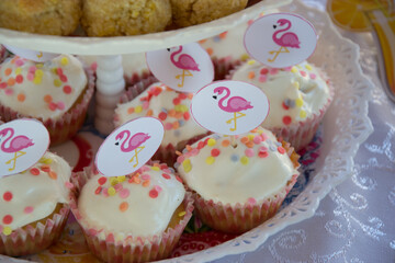 Close-up of homemade sweets with pink flamingo sticks decoration on cake-stand, party concept, sweets for birthday celebration