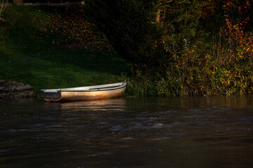 small boat on the river bank with reflections of the sun's rays