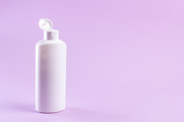 White plastic bottle with cream without label on a lilac background.