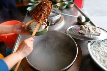 A Person frying noodles in a wok