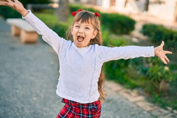 Adorable caucasian child girl with open arms  smiling happy at the city.