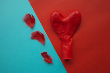 red feathers and red heart on the blue and red background for valentine's day