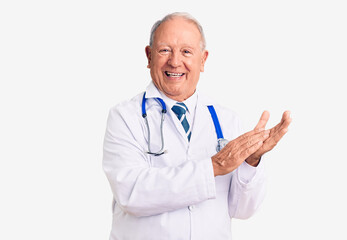 Senior handsome grey-haired man wearing doctor coat and stethoscope clapping and applauding happy...