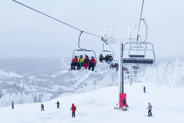 Fototapeta na wymiar chairlift and downhill skiers in a winter hilly landscape