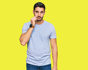 Young hispanic man wearing casual clothes mouth and lips shut as zip with fingers. secret and...