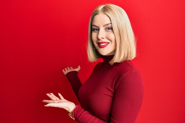 Naklejka premium Young blonde woman wearing casual clothes inviting to enter smiling natural with open hand