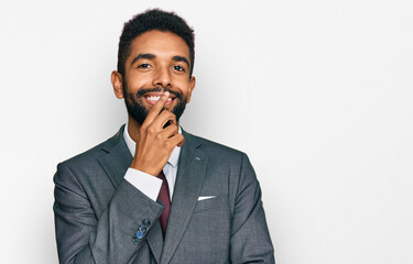 Young african american man wearing business clothes looking confident at the camera with smile with crossed arms and hand raised on chin. thinking positive.