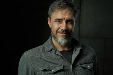 Fototapeta na wymiar Portrait of casual older man with beard against dark background.