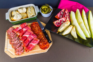 Platters of cured meats, fruit, bread and gherkins.