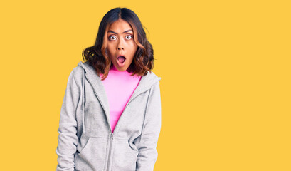 Fototapeta premium Young beautiful mixed race woman wearing casual sporty clothes afraid and shocked with surprise expression, fear and excited face.